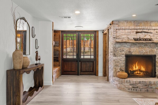 A foyer with a stone fireplace, wooden doors, and a console table with decorative items.