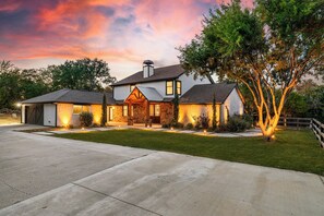 A two-story house with a garage, stone exterior, and a well-maintained lawn.