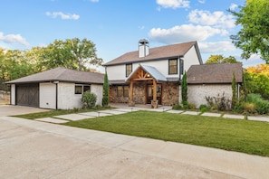 A two-story house with a stone facade, a front porch, and a garage. - The Castle Creek Ranch - 5-Acre Ranch, Private Pool, Game Room & Country Getaway (Cross Roads)