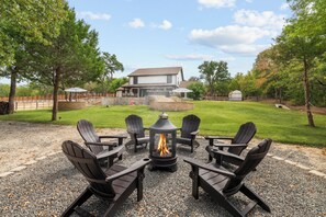 An outdoor seating area with four Adirondack chairs and a central fire pit.