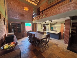A kitchen with a dining area, featuring a brick wall, a large window, and a built-in stove. - 10 minutes from Beach Park - House with sea view 50m from the beach (Aquiraz)