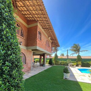 A brick house with a covered patio, a swimming pool, and a well-maintained lawn. - 10 minutes from Beach Park - House with sea view 50m from the beach (Aquiraz)