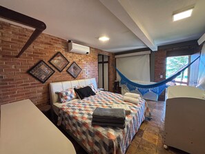 Ein Zimmer mit einem Bett, einer Hängematte, einer Ziegelwand und gerahmten Bildern.