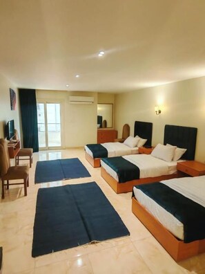 Habitació d'hotel amb tres llits, una taula i una cadira.