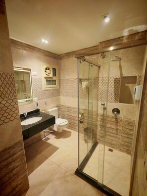 Un bany amb plat de dutxa tancat per vidre, un lavabo i un vàter.