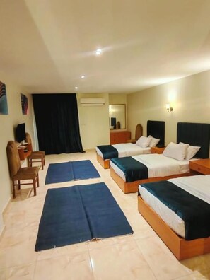 Habitació d'hotel amb dos llits, escriptori, cadira i una finestra gran.