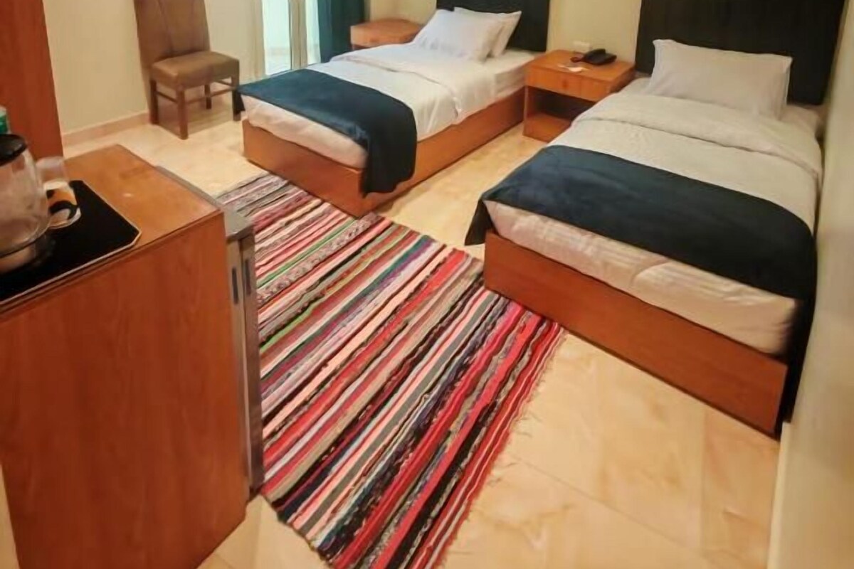Habitació d'hotel amb dos llits, un escriptori i una cadira.
