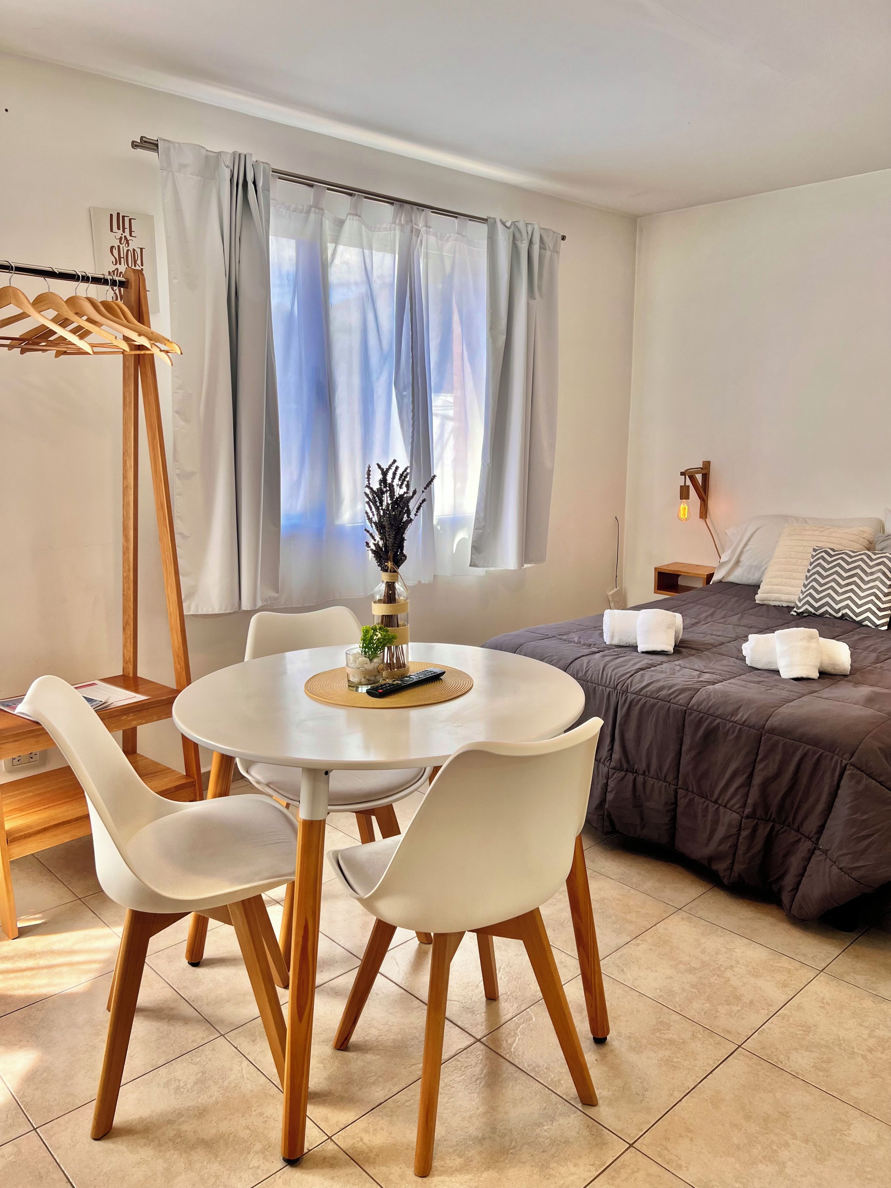 Quarto moderno com cama, mesa de cabeceira e janela com cortinas.