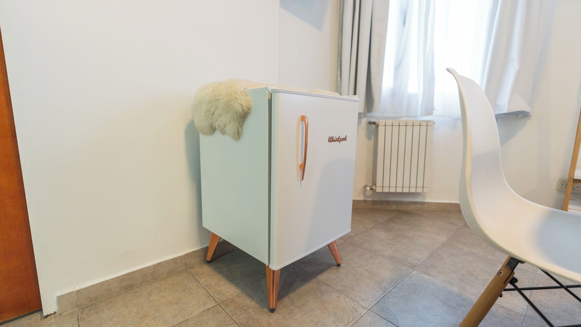 Une petite cuisine équipée comprenant un réfrigérateur, une chaise et un radiateur.