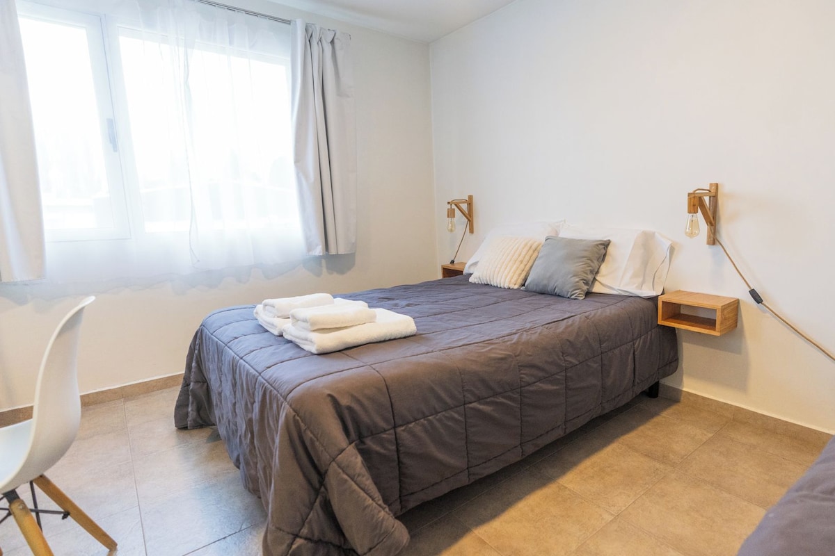 A bedroom with a bed, bedside tables, a chair, and a window with curtains.