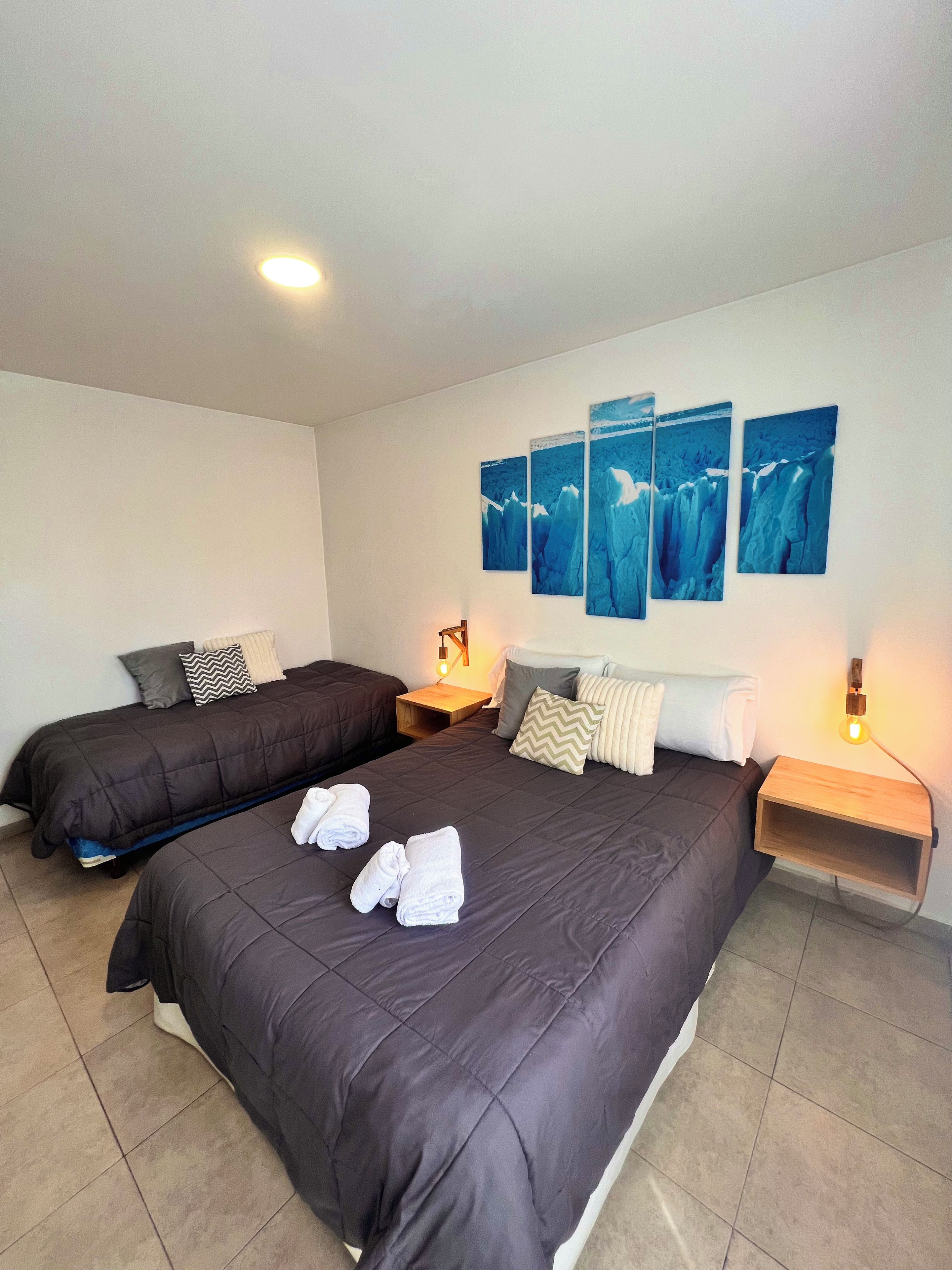 Une chambre d’hôtel avec deux lits, une table de chevet avec une lampe et des œuvres d’art murales.