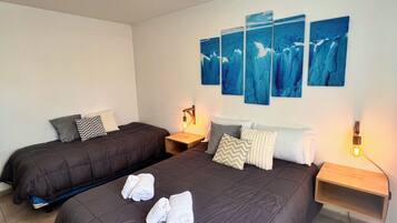 Une chambre d’hôtel avec deux lits, une table de chevet avec une lampe et des œuvres d’art murales.