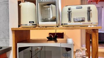 A kitchen with a microwave, a coffee maker, and a toaster on a wooden shelf.