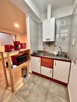 A compact kitchen with a built-in stove, a coffee maker, and a sink.