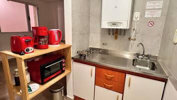 A compact kitchen with a microwave, coffee maker, and a gas stove.
