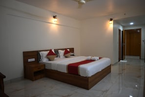 A hotel room with a large bed, bedside tables, a wooden headboard, and a tiled floor. - Reunion D Square Hotels & Resorts (Kundapur)