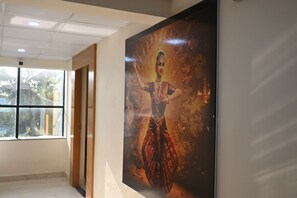 A corridor with a large poster of a dancer, a window with a view of greenery, and a door.