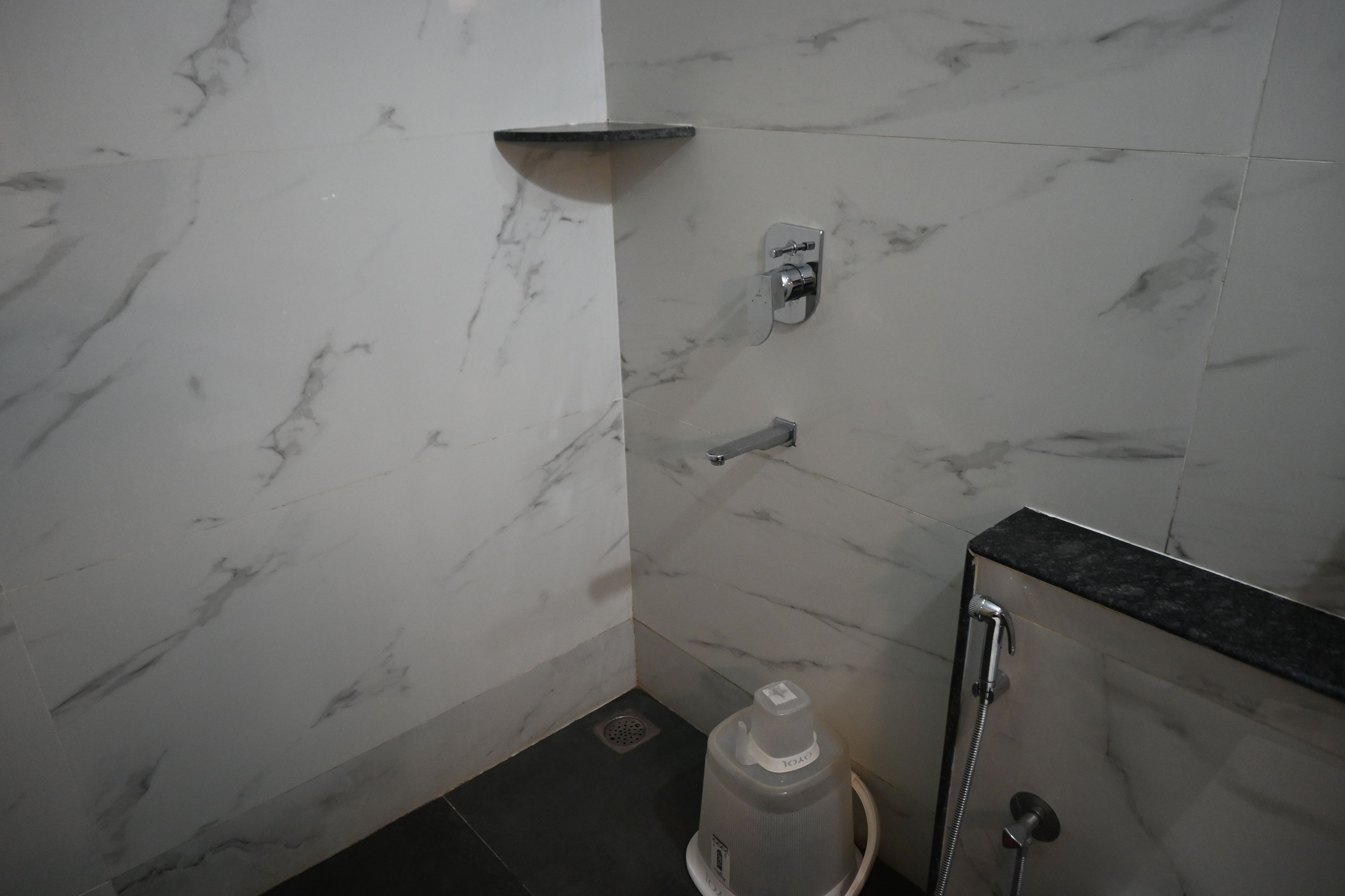 A bathroom with a marble wall, a shower, and a sink.