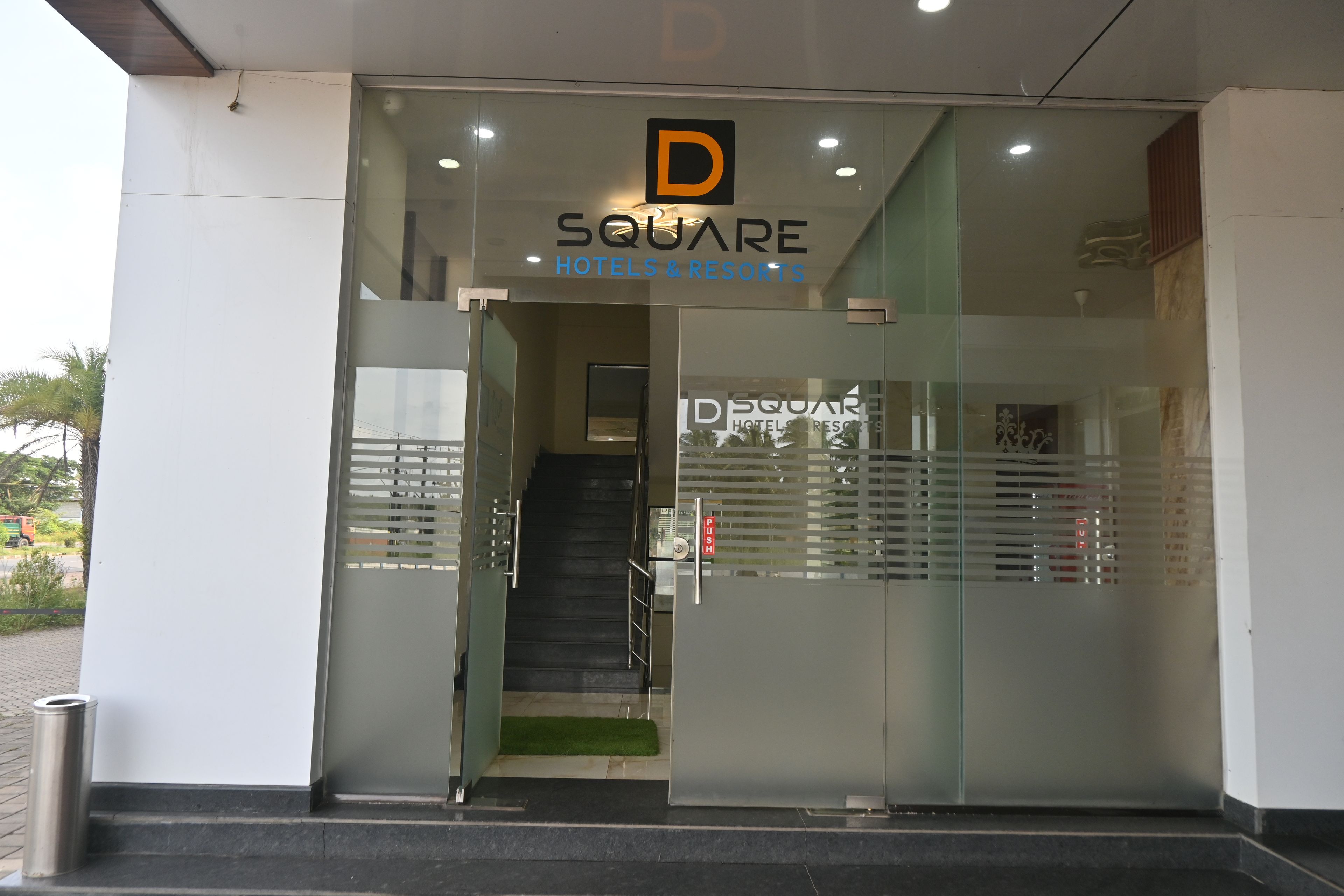 A hotel entrance with a glass door, a staircase leading inside, and a sign above the door.