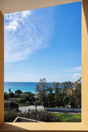 Ein Balkon mit Blick auf das Meer, Bäume und einen klaren Himmel.