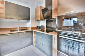 A modern kitchen with built-in appliances, a large oven, and a coffee maker. - Wifi, 350m from ski slopes, Ground floor, balcony, ski locker, 60m², Les Gets (Les Gets)