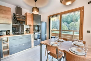 A modern kitchen with a dining area, large windows, and a view of the outdoors. - Wifi, 350m from ski slopes, Ground floor, balcony, ski locker, 60m², Les Gets (Les Gets)