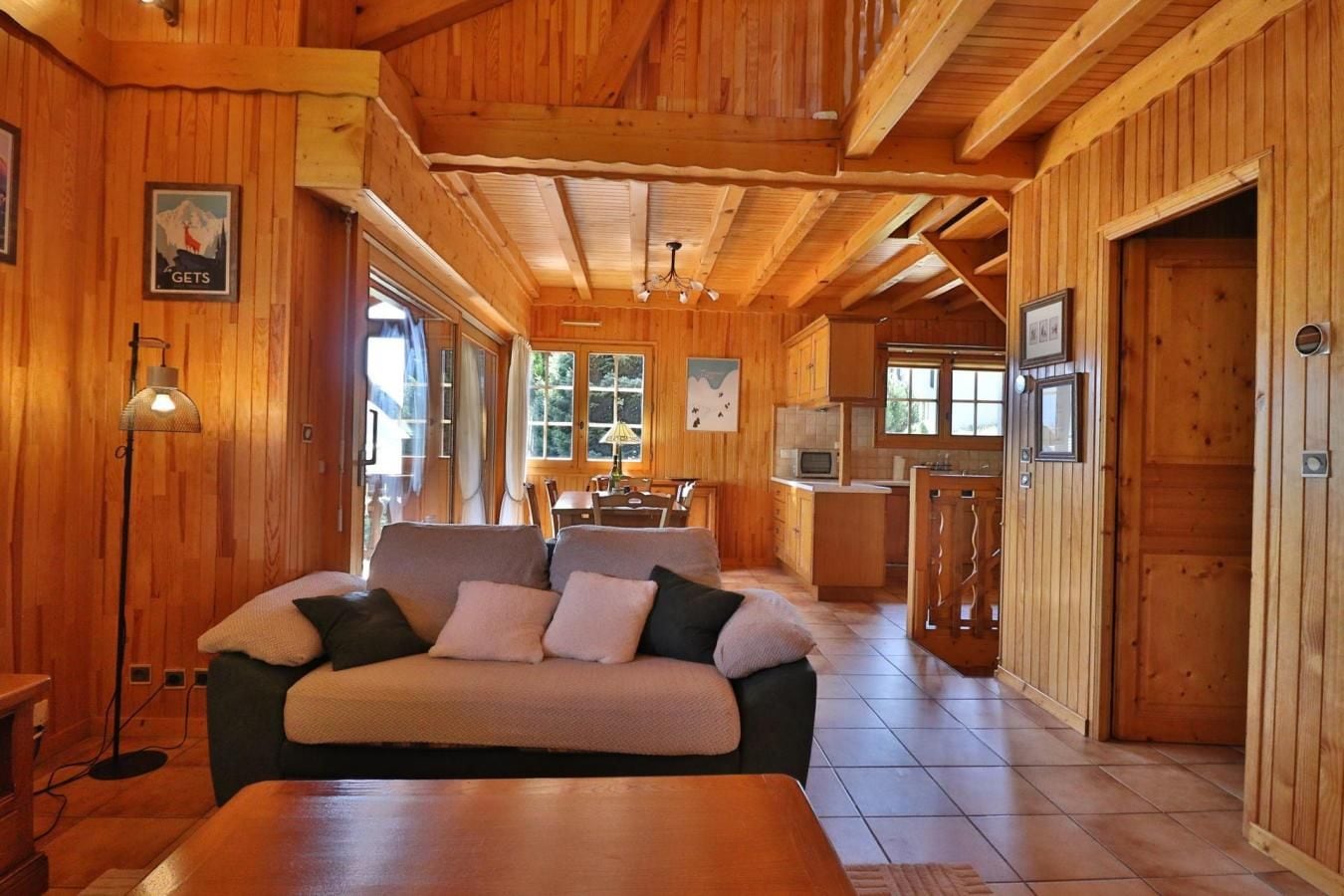Et interiør i træ med en sofa, et spisebord og et køkkenområde.