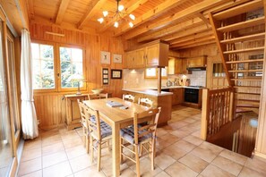 A wooden interior with a dining table, chairs, kitchen area, and a staircase. - Chalet, wifi, Ground floor, terrace, balcony, fireplace or stove, parking, 94m², Les Gets (Les Gets)