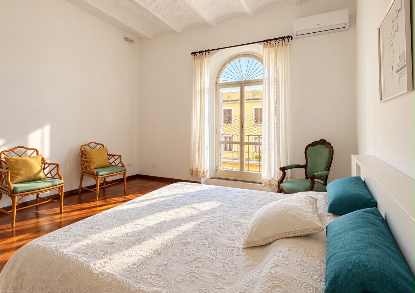 Une chambre avec un grand lit, deux chaises, une fenêtre avec des rideaux et un appareil de climatisation.