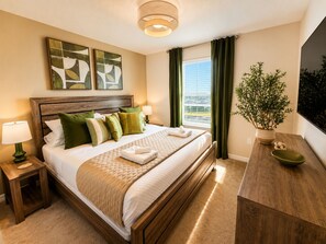 A hotel room with a wooden bed, green and white pillows, a bedside table with a lamp, a potted plant, and artwork on the wall. - Sunrise Views, Park Adventures, Fireworks Nights - Epic Fireworks Retreat (Davenport)