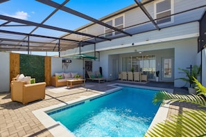 A modern outdoor pool area with a glass ceiling, lounge chairs, and a seating area with a table. - Sunrise Views, Park Adventures, Fireworks Nights - Epic Fireworks Retreat (Davenport)