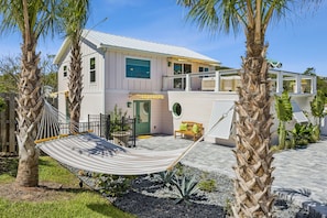 A two-story house with a hammock in the front yard, a small patio, and a yellow bench. - Sunday Best - Steps from the beach (Fernandina Beach)