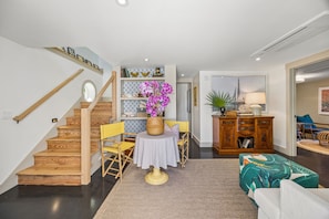 A staircase leading to a landing with a table and chairs, a wooden cabinet, and a bed in the adjacent room. - Sunday Best - Steps from the beach (Fernandina Beach)