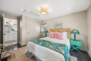 A bedroom with a bed, bedside tables, a dresser, and a mirror. - Sunday Best - Steps from the beach (Fernandina Beach)