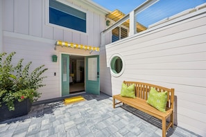 A building with a green door, a wooden bench with green cushions, and a potted plant. - Sunday Best - Steps from the beach (Fernandina Beach)