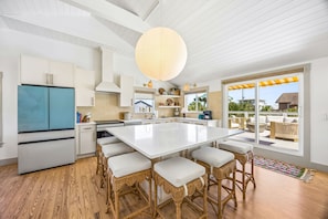 A modern kitchen with a large island, white cabinetry, and a view to an outdoor patio. - Sunday Best - Steps from the beach (Fernandina Beach)