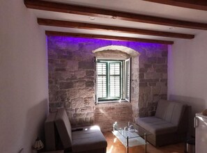 A cozy room with a stone wall, a window with shutters, a glass table, and two chairs. - Double bedroom with King sized bed and Old City View - A1 (Split)