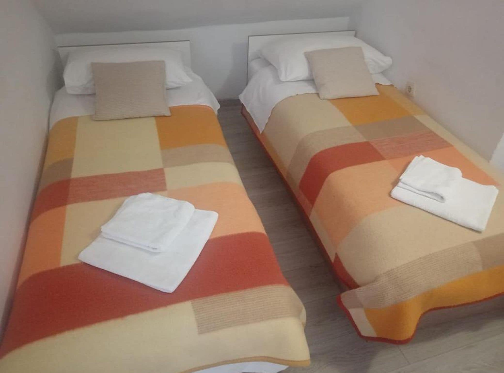 Two single beds with white linens and a checkered bedspread.