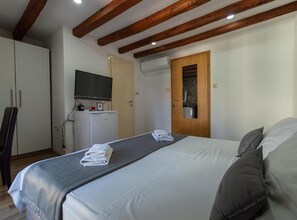 A hotel room with a bed, a TV, a wardrobe, and a bathroom door. - Double Room with Separate beds and Old City View - A2 (Split)