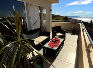 Un balcone con mobili da esterno, un tavolo con tovaglia rossa e vista sul mare.