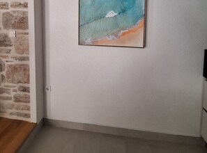 A room with a stone wall, a painting of a beach scene, and a tiled floor. - Two Bedroom Holiday Home with Outdoor Swimming Pool (Murter)