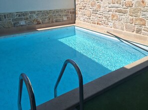 A swimming pool with a stone wall and a metal ladder. - Two Bedroom Holiday Home with Outdoor Swimming Pool (Murter)