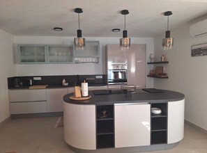A modern kitchen with a curved island, stainless steel appliances, and pendant lighting. - Two Bedroom Holiday Home with Outdoor Swimming Pool (Murter)