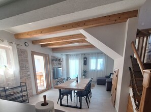 A spacious dining area with a long wooden table and chairs, a stone wall, and a staircase leading to an upper level. - Two Bedroom Holiday Home with Outdoor Swimming Pool (Murter)