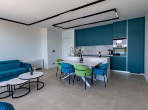 A modern kitchen with a dining area, a sofa, and a coffee table. - Six Bedroom Sea View Villa with Two Swimming Pools (Blace)