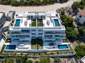 A multi-story hotel with rooftop pools and a central courtyard. - Six Bedroom Sea View Villa with Two Swimming Pools (Blace)