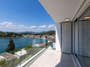 A balcony with a clear view of a lake and a town in the background. - Six Bedroom Villa with Sea View & Two Pools (Blace)