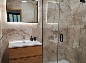 A modern bathroom with a marble wall, a wooden vanity, a mirror, and a glass shower enclosure. - Two-Bedroom Apartment in Ground Floor with Terrace (Orebic)