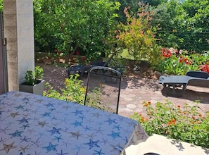 An outdoor patio area with a table and chairs, surrounded by greenery and flowers. - Two-Bedroom Apartment in Ground Floor with Terrace (Orebic)