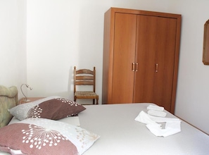 A bedroom with a bed, pillows, a chair, and a wardrobe. - Two-Bedroom Apartment in Ground Floor with Terrace (Orebic)